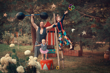 Family portrait in vintage circus style. Father is dressed as a strongman with barbell, son is...