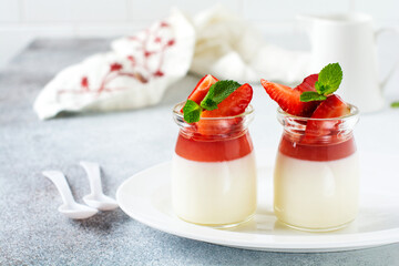 Vanilla panna cotta and fresh strawberry, mint leaves on gray concrete table background. Festive...