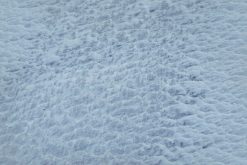 Texture of snow ripples on the field close-up. Selective focus. Natural blue background.