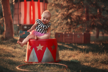 Cute little funny girl dressed like a circus actress is on the circus pedestal. Image with...