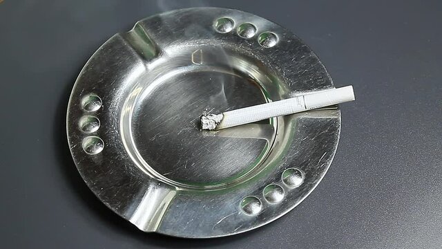 The cigarette is smoldering in the ashtray