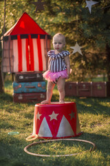Cute little funny girl dressed like a circus actress is on the circus pedestal. Image with selective focus and toning © Smolina