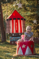 Cute little funny girl dressed like a circus actress is on the circus pedestal. Image with...