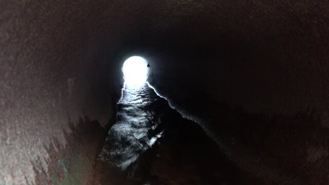 Big culvert under the highway. The video operator is on the water in the pipe and shoots a movie