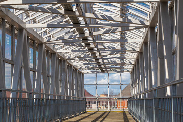 long overhead pedestrian crossing in white on a bright sunny day
