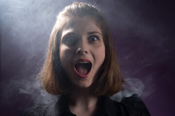portrait of a surprised young girl, opening her mouth, laughing, against the background of the smoke of a viper