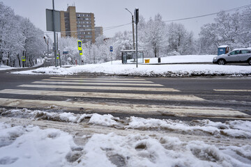 Wet snow-covered road and pedestrian crossing in the city
