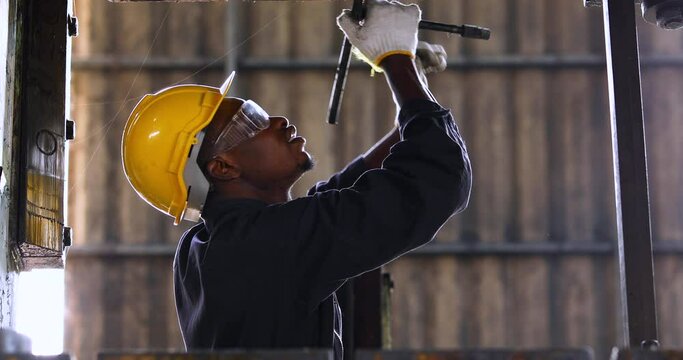 Young black male engineer checking checking and repair the machine in Heavy Industry Manufacturing Facility. Service and Maintenance of factory machinery. American African people.