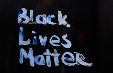 Handwritten activist message to show protest agains racism 'Black lives matter'. Text message 'Black lives matter' on glass using brush and paint. Black background. High quality photo