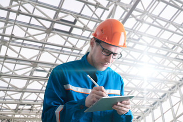 male worker in uniform holding and using a tablet