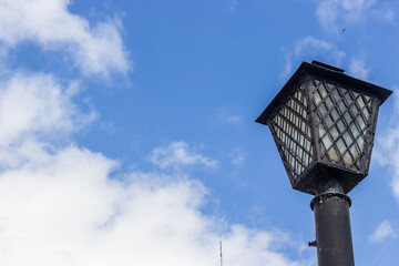 Cast iron vintage lantern on the background of the summer sky.