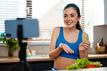 Obraz na płótnie Canvas White young woman preparing salad while taking selfie footage