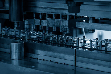 Close-up scene of progressive die operation. The metal work processing by stamping die. - obrazy, fototapety, plakaty