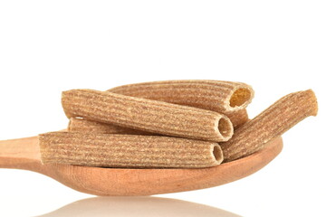 Dark brown, uncooked, organic rye pasta with wooden spoon, close-up, isolated on white.