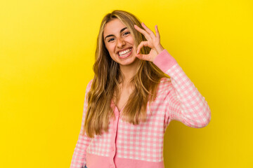 Obraz na płótnie Canvas Young blonde caucasian woman isolated on yellow background cheerful and confident showing ok gesture.