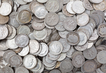 Wide view of old silver dimes illuminated with natural light.