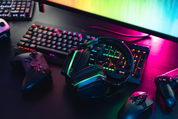 gamer work space concept, top view a gaming gear, mouse, keyboard, joystick, headset with rgb color on black table background.