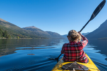 Young woman paddling a kayak touring the lakes of the National Park. Patagonia, Argentina. - obrazy, fototapety, plakaty