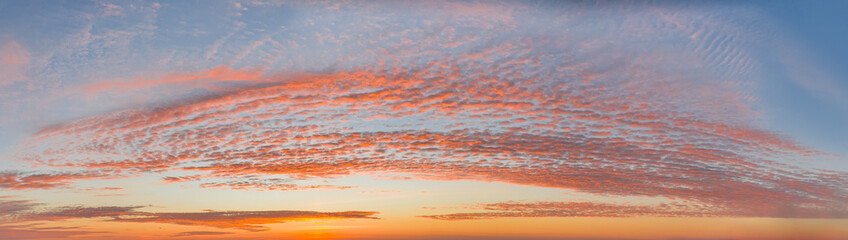 intense dramatic panoramic sunset with cirrus clouds illuminated by red sunbeams