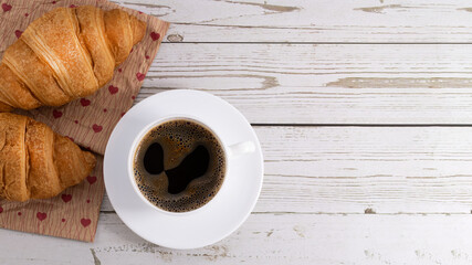 fresh croissants and coffee on light wooden background with copy space