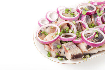 Salted herring with rings of red onion rings on oval plate on a light background . Marinated sliced fish. Traditional russian appetizer