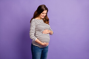 Photo of charming lady waiting baby dressed striped shirt hugging looking tummy isolated violet...