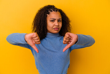 Young african american woman isolated on yellow background showing a dislike gesture, thumbs down....