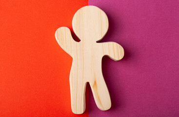 A figurine of a man carved from solid pine with a hand jigsaw. On a multi-colored background