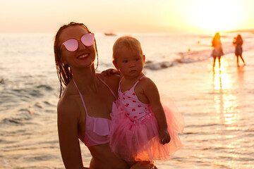 Young woman and baby at sunset on the sea
