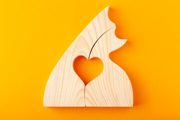 A figurine of hugging cats, carved from solid pine by a hand jigsaw. On a yellow background