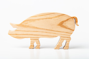 Pig figurine carved from solid pine by hand jigsaw. On a white background