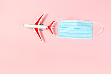 Airplane model with red wings with a blue medical mask. online ticketing and tourism concept during covid pandemic