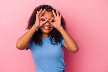 Young african american woman isolated on pink background showing okay sign over eyes