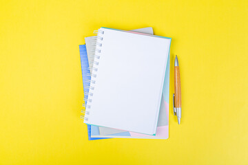 open spiral notepad on a yellow background with a pen. top view, stack of notepad with blank sheet. school concept, businessman work