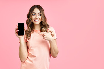 Excited woman pointing her finger at mobile phone and looking to copy space
