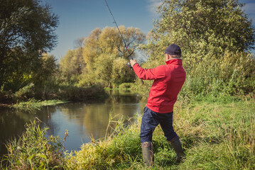 Fishermen fishing with a spinning rod from the shore on a sunny day. Fishing on a sunny day. Man on the river bank throws a spinning rod.