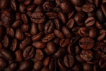 Roasted coffee beans on the old dark wooden background for wallpaper or decor