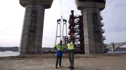 Male builders walking under bridge