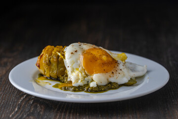 Baked potato with fried egg in white plate, close up