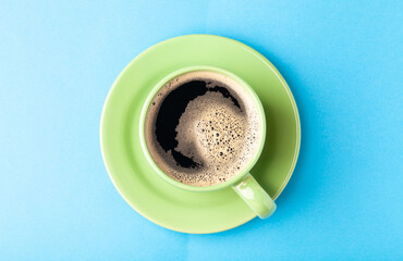 Hot fresh coffee with foam in the green cup on a color background