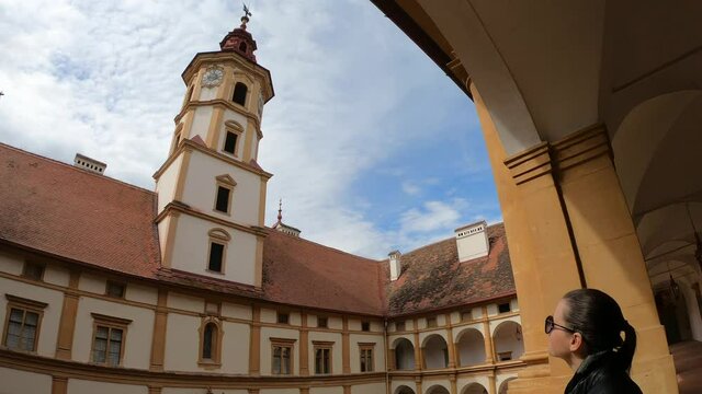 A woman in a black leather jacket enjoying the view on the bell tower of Eggenberg castle in Graz, Austria. There is a square patio in the middle part. Appreciation and contemplation of art
