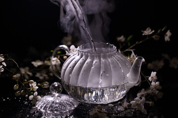 Flower tea in a transparent teapot on a black background