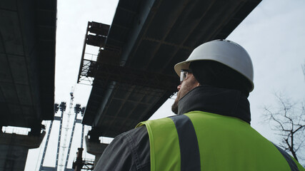 Adult contractor inspecting unfinished bridge