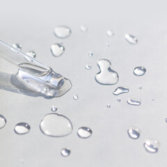 Liquid gel or serum pipette with drops on gray background