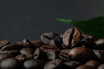 Roasted coffee beans with leaf on the old dark wooden background for wallpaper or decor. Shallow depth of field. Selected focuse. Toned