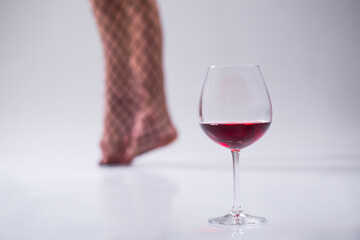 Sensual woman legs. Red wine glass. Wine glass. Photo. Alcohol. 