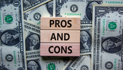 Pros and cons symbol. Wooden blocks with words 'Pros and cons'. Beautiful background from dollar...