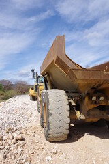 Obraz premium Engin de chantier et de travaux public jaune machines et camions pour faire des routes des autoroutes avec des gros pneus