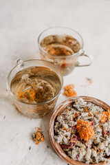 Herbal tea is brewed in glass cups on a light background. Herbal tea ingredients. Dried calendula, mint, Damascus rose, lemon balm, thyme, lavender, lemongrass.