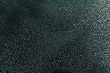 Raindrops on a fragment of the car close-up. Drops on a green metal background.